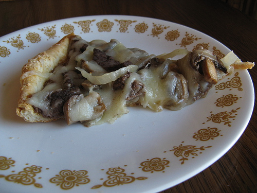 lice of steak pizza on a white patterned plate