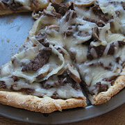 teak pizza with melted cheese on a metal pan