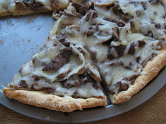 teak pizza with melted cheese on a metal pan