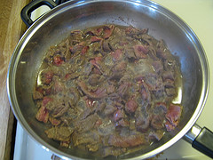 Sliced steak cooking with onions in a skillet