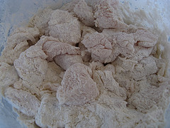 Raw chicken pieces coated in flour for frying