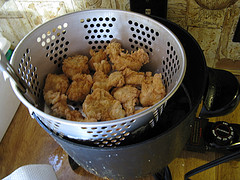 Fried chicken bites draining in a colander
