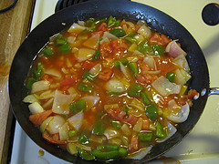 Bell peppers onions and pineapple simmering in sweet and sour sauce
