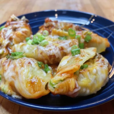 Prepared taco stuffed shells on blue plate.