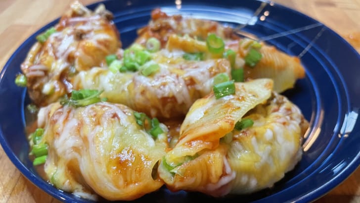 Prepared taco stuffed shells on blue plate.