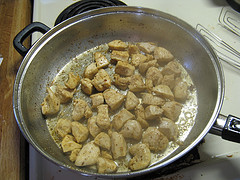 Chicken pieces cooking in a skillet with seasoning