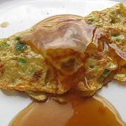 Egg foo yung patty topped with sauce on a white plate.