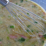 Uncooked egg foo yung batter with vegetables in a mixing bowl.