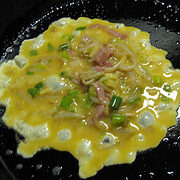 Egg foo yung mixture cooking in a skillet with vegetables and meat.