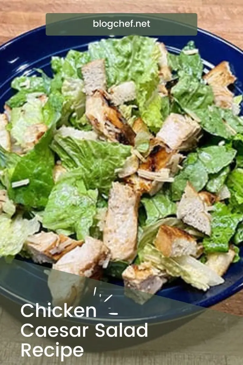 Top view of prepared chicken Caesar salad on blue plate.