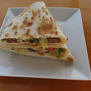 Grilled steak quesadilla cut into wedges on a white plate