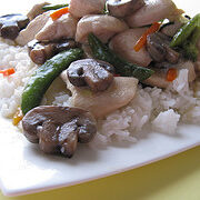 Moo goo gai pan served over white rice on a white plate