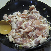 Raw sliced chicken and mushrooms in a black pan