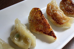 Crispy pot stickers with browned edges on a white plate