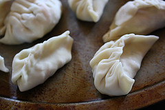 Uncooked pot stickers on a wooden board
