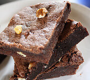 Two pieces of chocolate brownies with nuts on a white plate