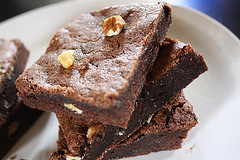 Two pieces of chocolate brownies with nuts on a white plate