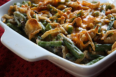 Green bean casserole topped with crispy fried onions in a white baking dish