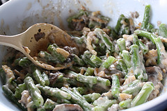 Green beans and mushrooms in a pot with sauce being stirred