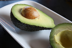 Halved avocado with seed on white plate