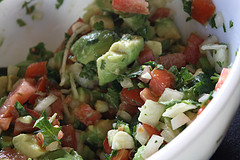 Bowl of guacamole mixture with diced vegetables