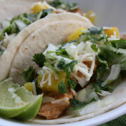 Taco filled with grilled pork, pineapple, cheese, onion, and cilantro with lime wedge