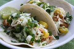 Taco filled with grilled pork, pineapple, cheese, onion, and cilantro with lime wedge