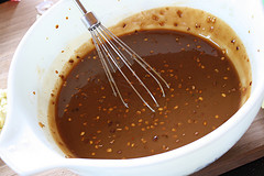 Bowl of Mongolian sauce with whisk and red pepper flakes