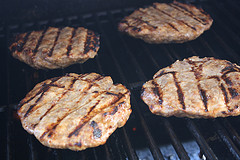 Beef patties cooking on the grill with visible char lines