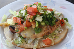 Grilled beef patty wrapped in a toasted quesadilla with lettuce, tomato, cheese, and sauce