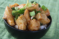 Crispy chicken pieces topped with green onions in a bowl