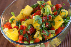 Glass bowl of mango salsa with bright mango chunks, peppers, and herbs