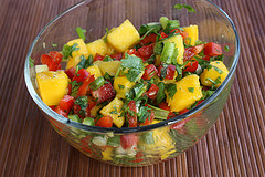 Glass bowl of mango salsa with bright mango chunks, peppers, and herbs