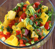 Glass bowl of mango salsa with bright mango chunks, peppers, and herbs