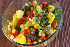 Glass bowl of mango salsa with bright mango chunks, peppers, and herbs