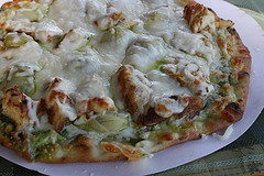 Baked chicken pesto pizza topped with melted mozzarella cheese on a plate
