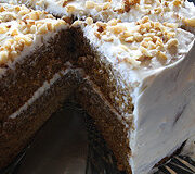 Whole spice cake with cream cheese frosting and chopped walnuts.