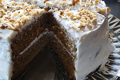 Whole spice cake with cream cheese frosting and chopped walnuts.