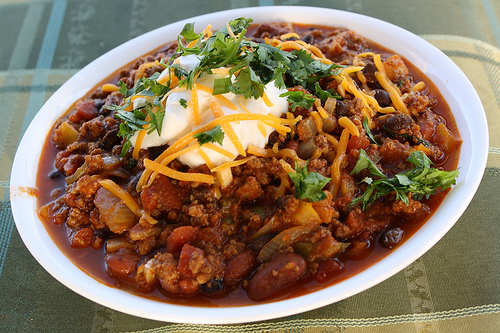  Pumpkin chili served in a white bowl with melted cheese and fresh parsley on top