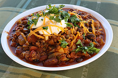  Pumpkin chili served in a white bowl with melted cheese and fresh parsley on top