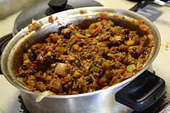 Pot of pumpkin chili with beans, vegetables, and meat on a stovetop