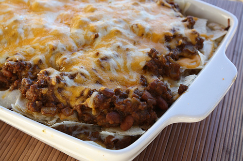 Baked burrito casserole with melted cheese on top in a white dish