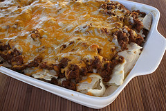 Baked burrito casserole with melted cheese on top in a white dish