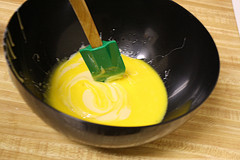 Bowl with yellow key lime pie filling being mixed with a green spatula