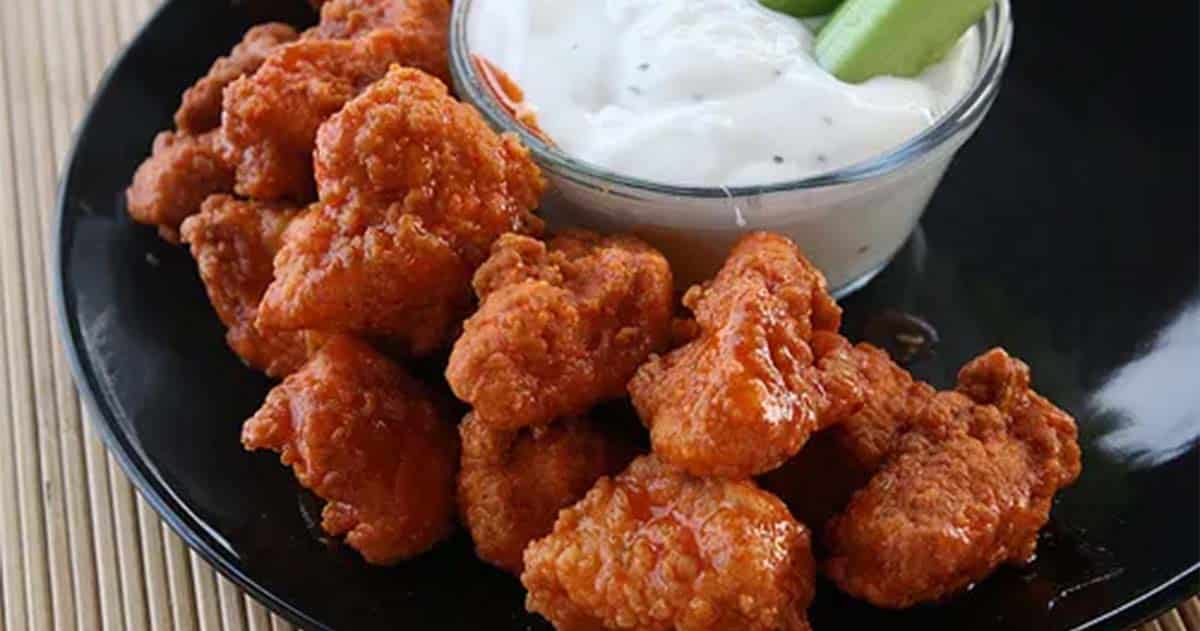 Boneless buffalo chicken wings on dish with ranch sauce.