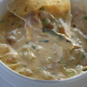 Bowl of creamy chili con queso dip with tortilla chip