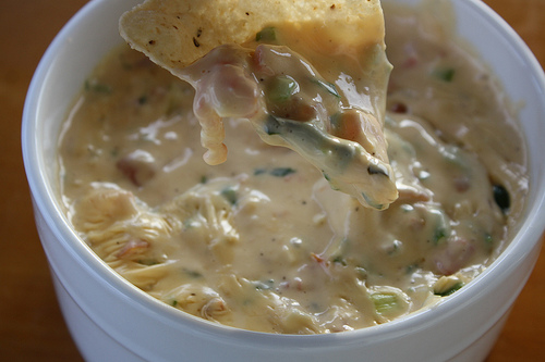 Bowl of creamy chili con queso dip with tortilla chip