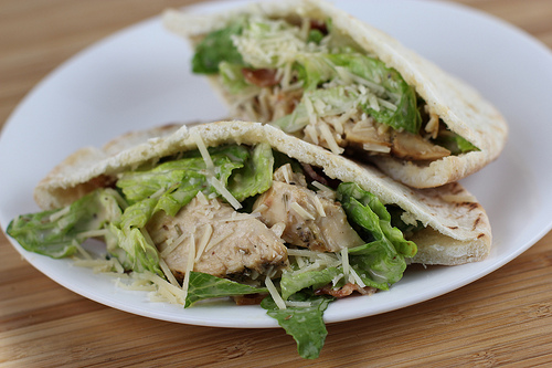 Chicken caesar pita halves on a white plate