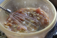 Raw chicken marinating in garlic sauce with whisk in bowl