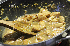 Chicken cooking in garlic sauce in wok with wooden spoon